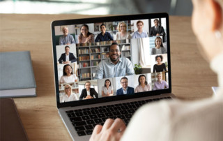 Image of a man on a laptop with a video conference on screen